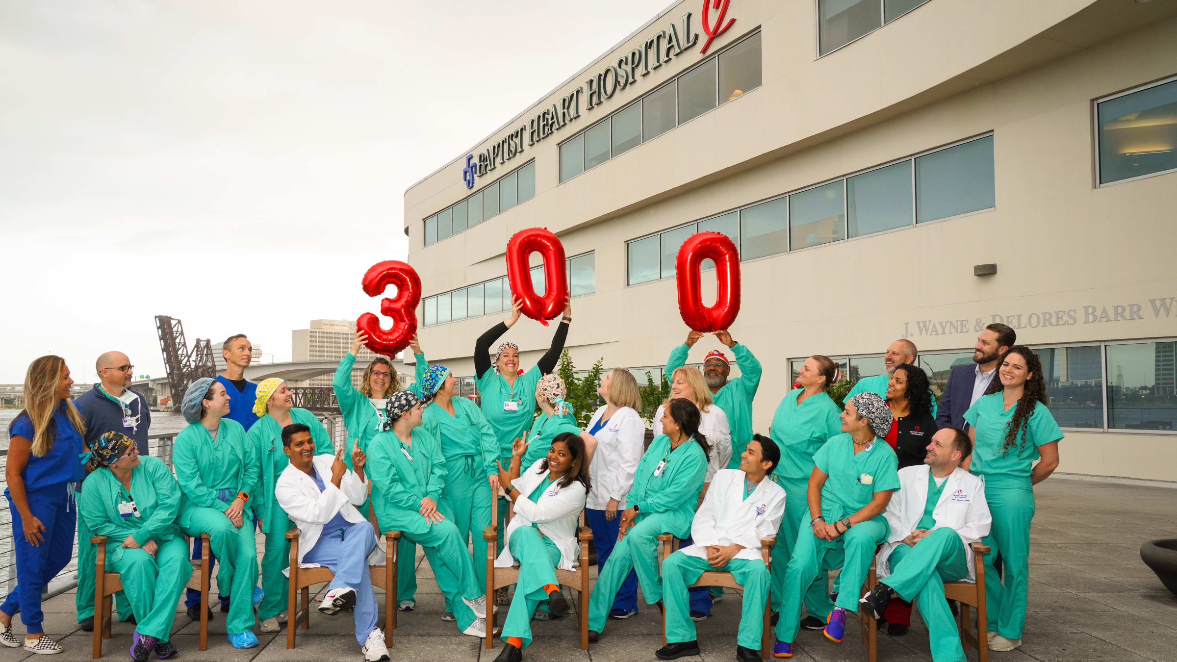 large group photo of providers holding up balloons in front of Baptist Heart Hospital