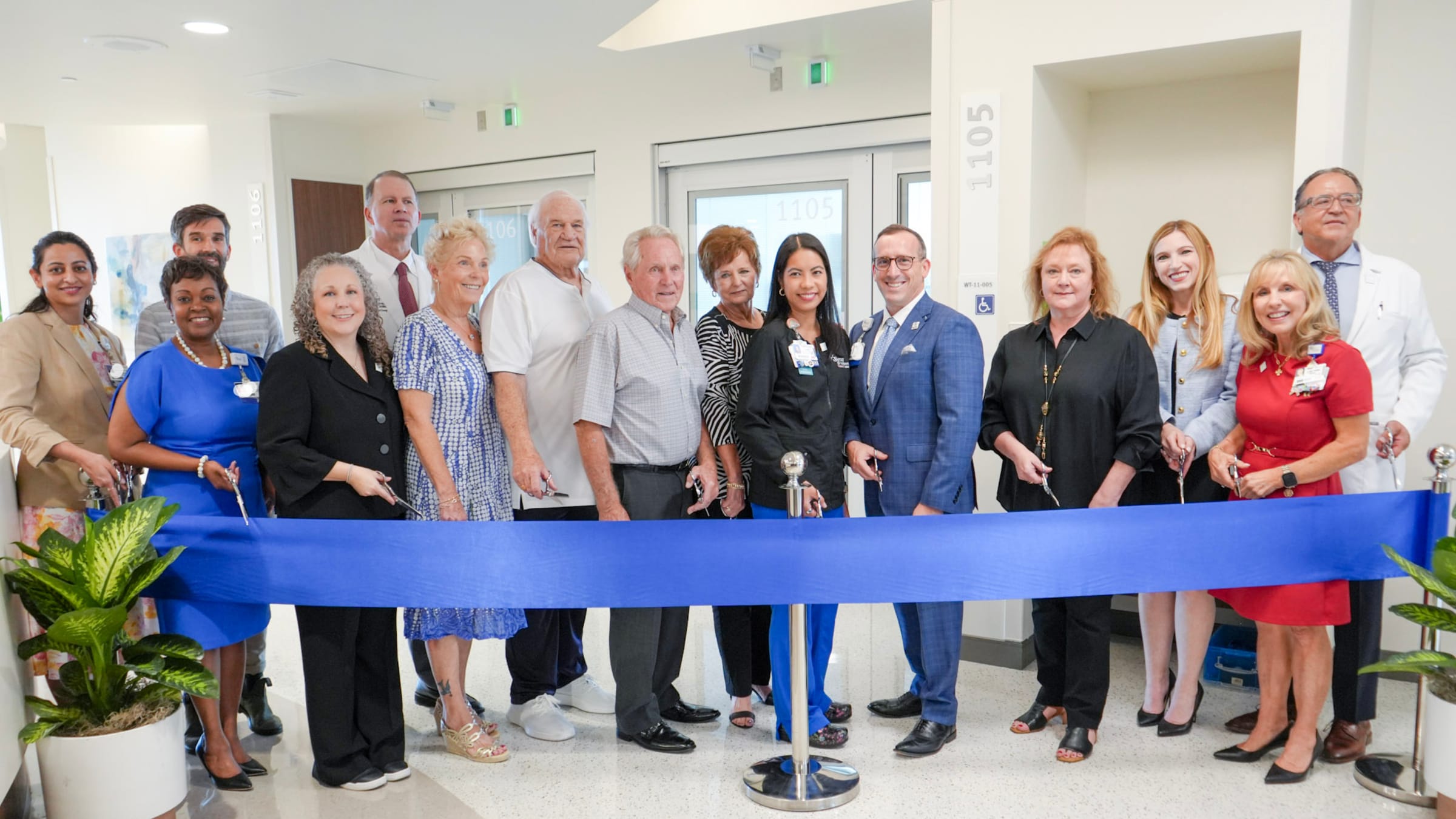Baptist Health leaders, physicians, board members, patients and philanthropists gather in front of a blue ribbon to celebrate the ribbon cutting event and opening of the  Cellular Therapy and Stem Cell Transplant Unit.