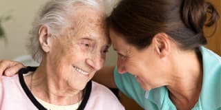 an elderly woman being embraced by a younger woman