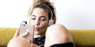 teenage girl sitting on a couch listening to music