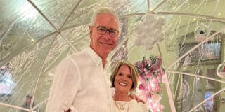 smiling couple posing in front of Christmas decorations