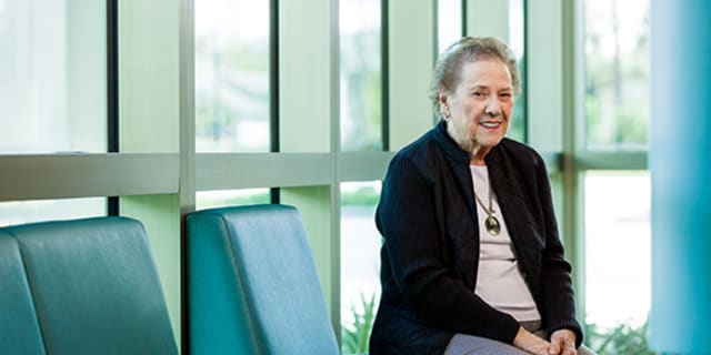 elderly female patient smiles in front of glass windows