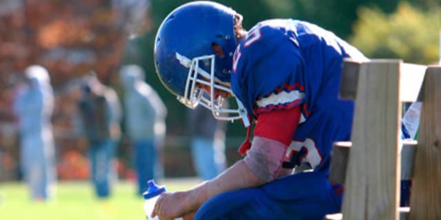Football player on the bench holding a water bottle.