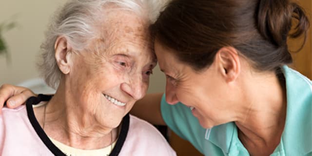 an elderly woman being embraced by a younger woman