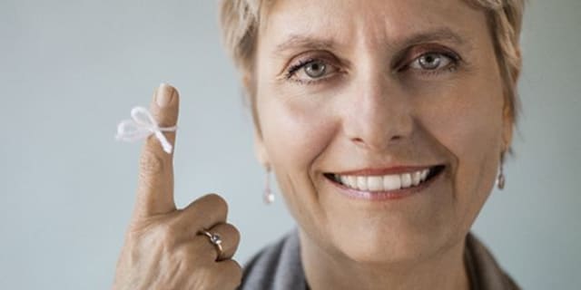 woman smiling with a piece of yarn tied in a bow around her finger
