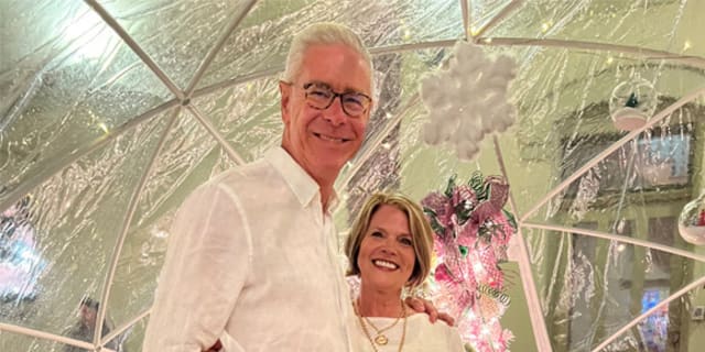 smiling couple posing in front of Christmas decorations