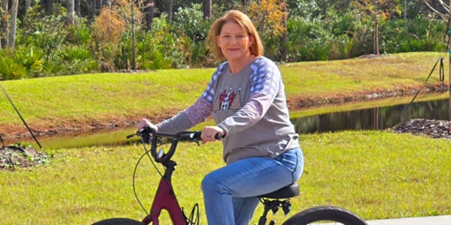 woman on a bike beside the sidewalk outside