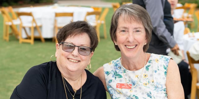 2 smiling woman sitting together outside