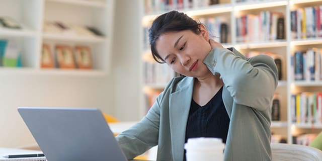 Woman sitting at computer with neck pain.
