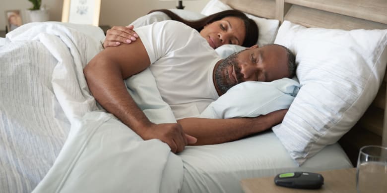 a black man and woman sleep peacefully in a bed together