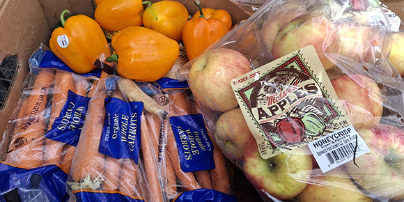 cardboard box filled with bell peppers, carrots and apples