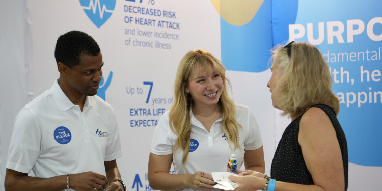 smiling Baptist employees talking with a woman at a Baptist event booth