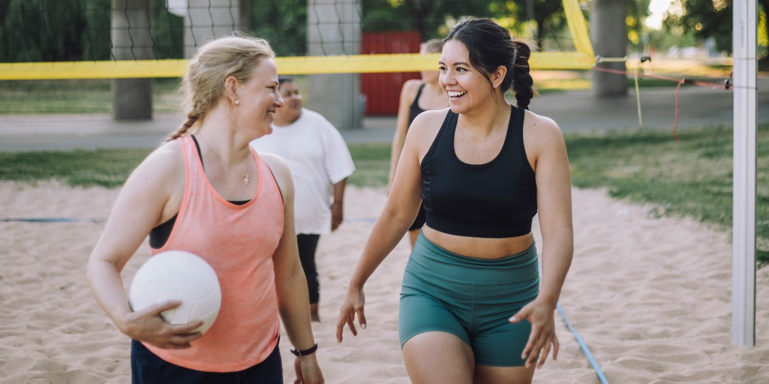 a group of female friends talking on a volleyball court