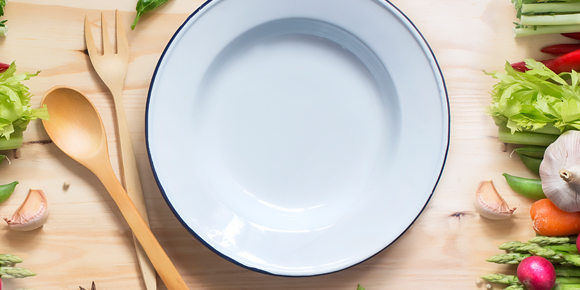 empty plate on a table with vegetables and wooden utensils