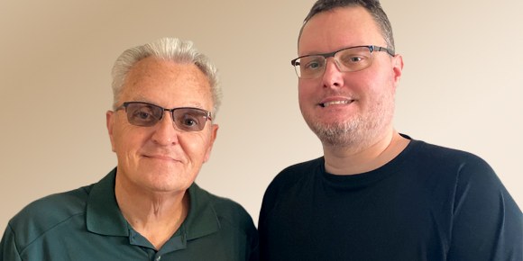 father and son standing next to each other in front of a blank wall