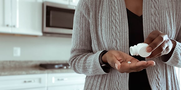 woman measuring out a pill in her kitchen