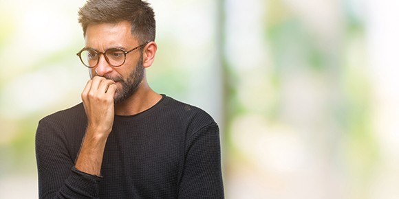 man in glasses nervously biting his nails