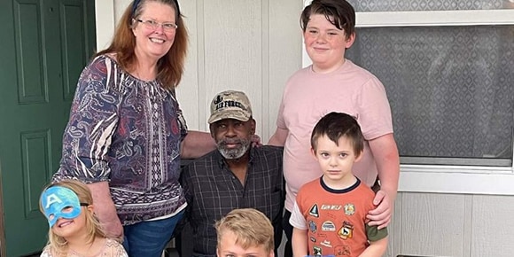 Valerie Sawyer poses with her family, including grandchildren, outside the front door of her home.