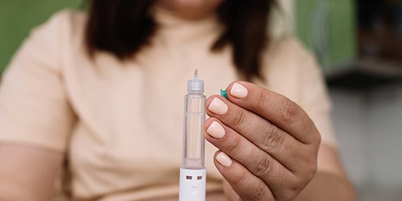 Weight Loss Drugs vs. Surgery: What's a better long-term solution?  Woman holding an injectable shot of weight loss drugs.