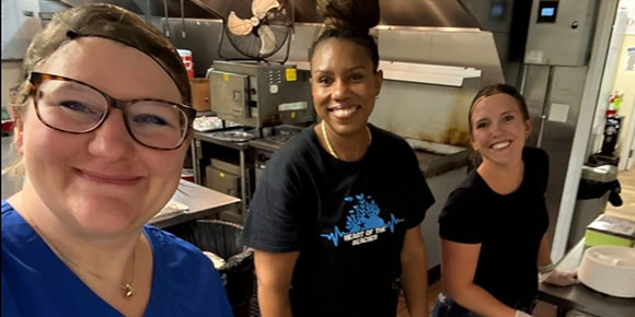 smiling volunteers in a kitchen serving food