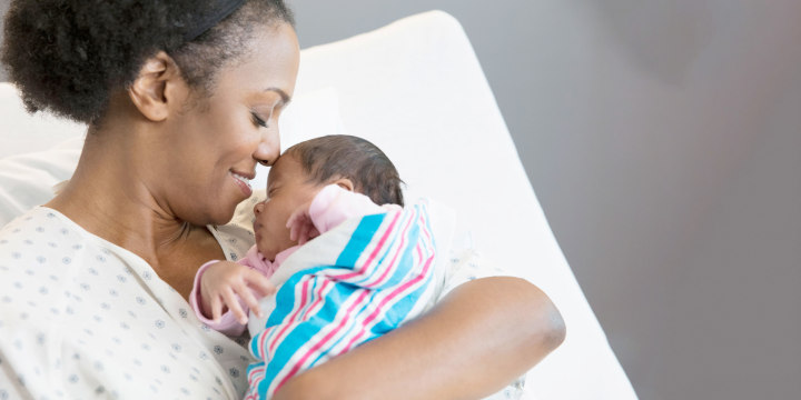 Mother holding newborn baby while in hospital bed