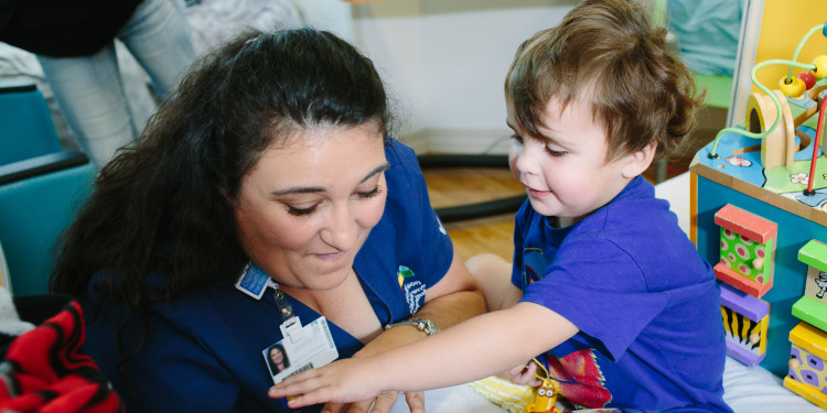 photo of a pediatric clinic setting where a female provider is reading a book with a young child