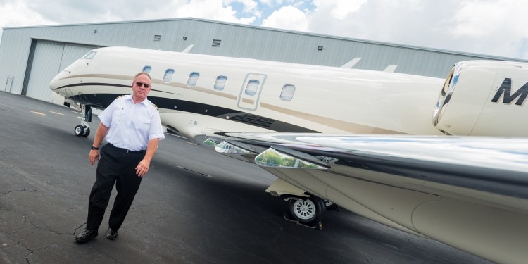 A male pilot who finally found a long-term weight loss solution with bariatric surgery poses in uniform by plane.