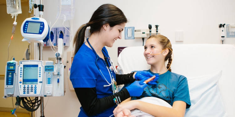 a nurse cares for a teenage patient lying in bed at the children's hospital.