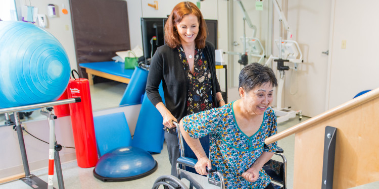 female therapist helping a woman get out of her wheelchair