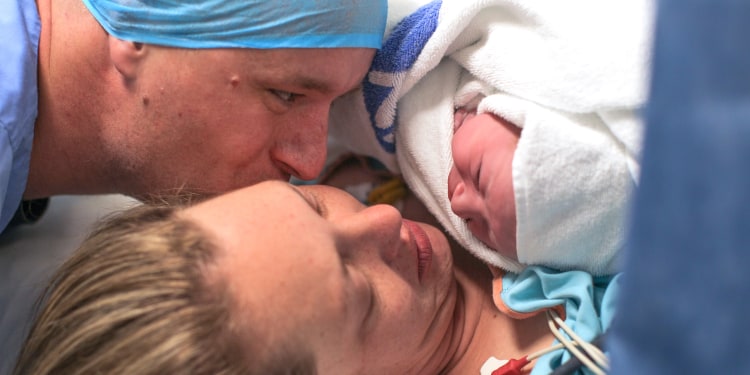 a husband and wife hold their newborn baby boy for the first time.
