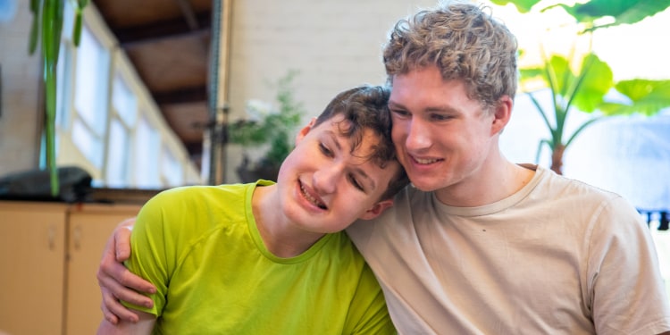 A boy with autism hugs his brother at breakfast