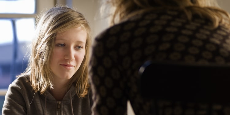 Photo of a teenage girl talking to a counselor