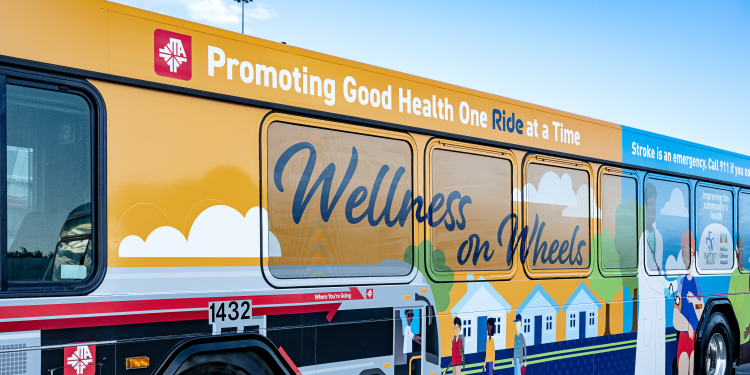 Colorful graphics on the side of the JTA and Baptist wellness on wheels bus.