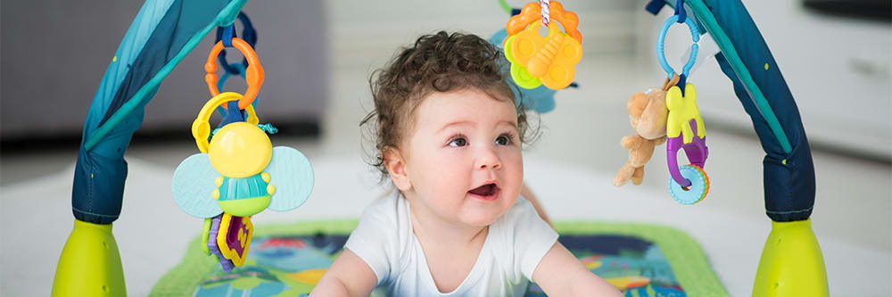 A baby plays on her tummy and looks at toys