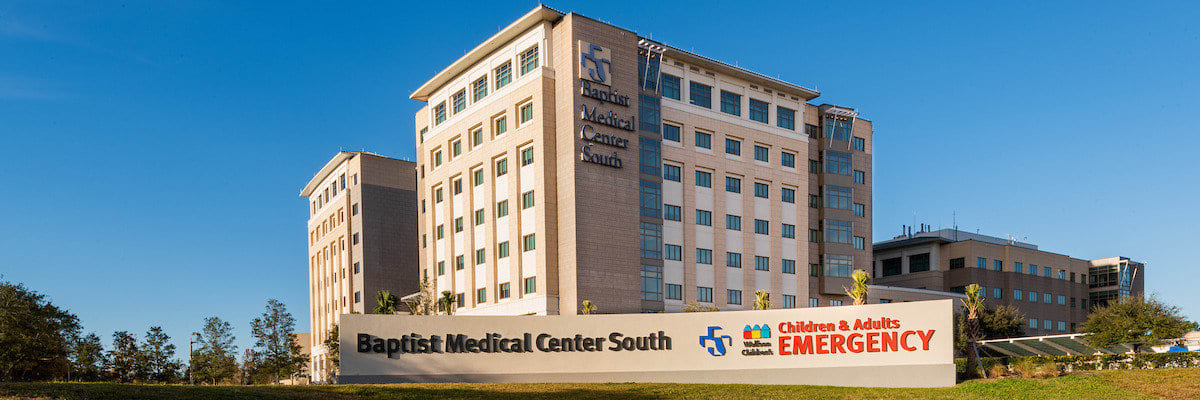 exterior photo of baptist medical center south with blue sky at top and a pond at the bottom reflecting the hospital.