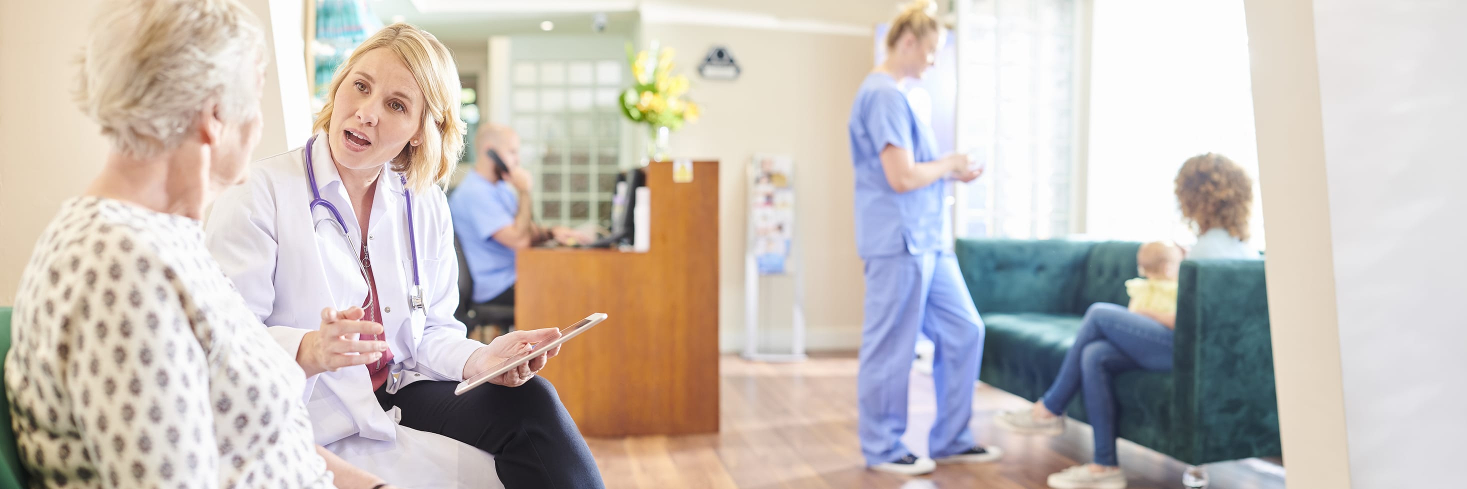 scene inside a doctor's office with patients talking to health care workers.