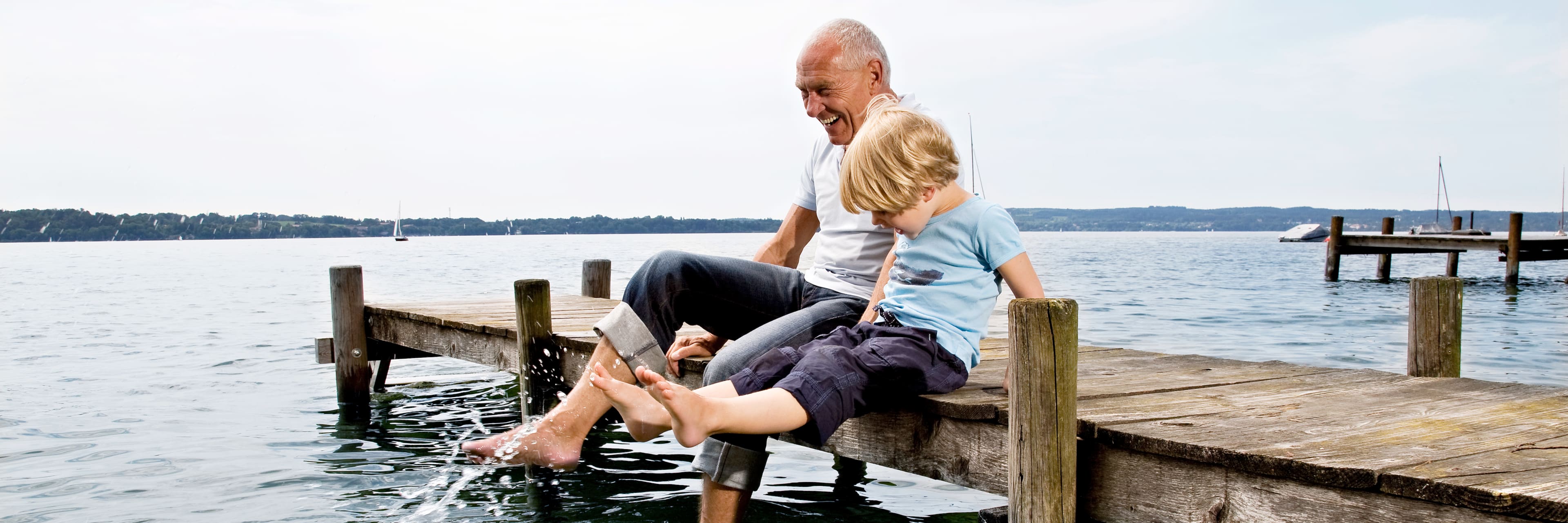 boy splashing with grandfather on dock at lake
