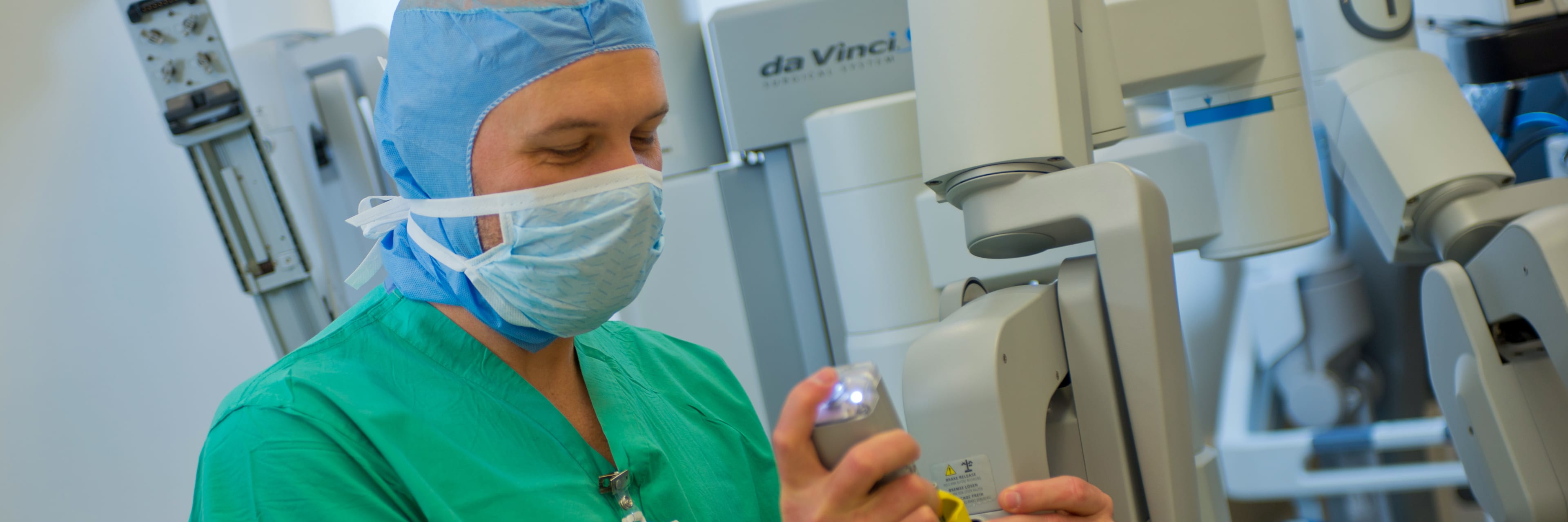 male health care worker preparing da Vinci machine for surgery