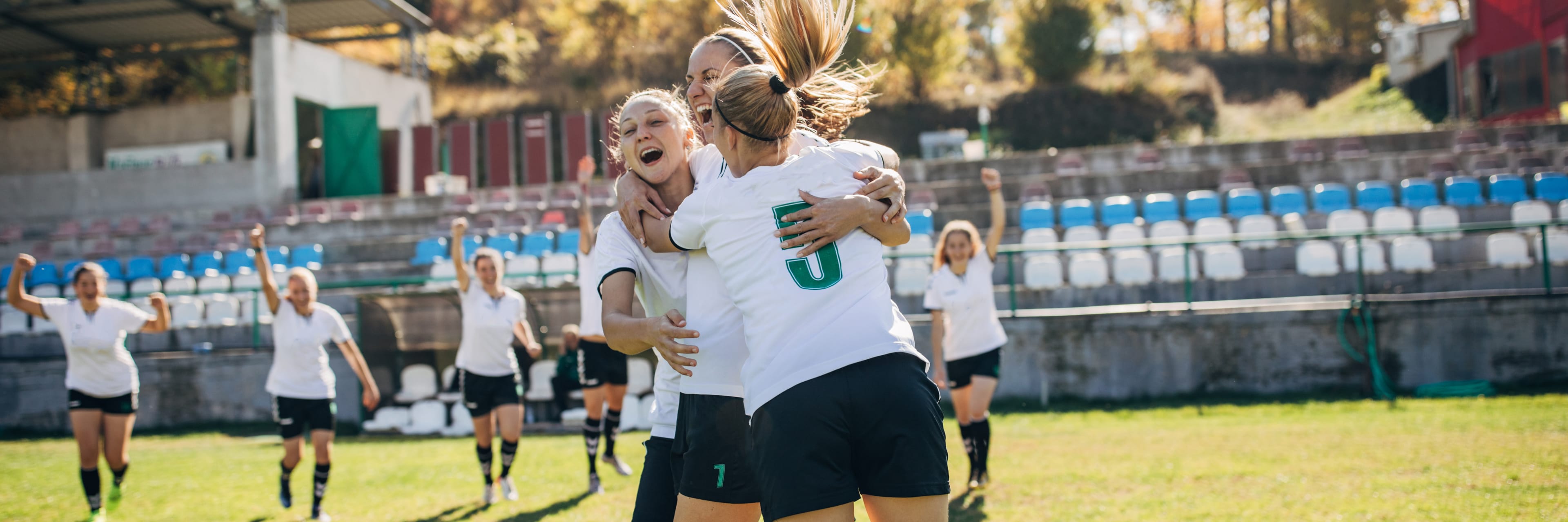 group of soccer girls celebrating together in a stadium