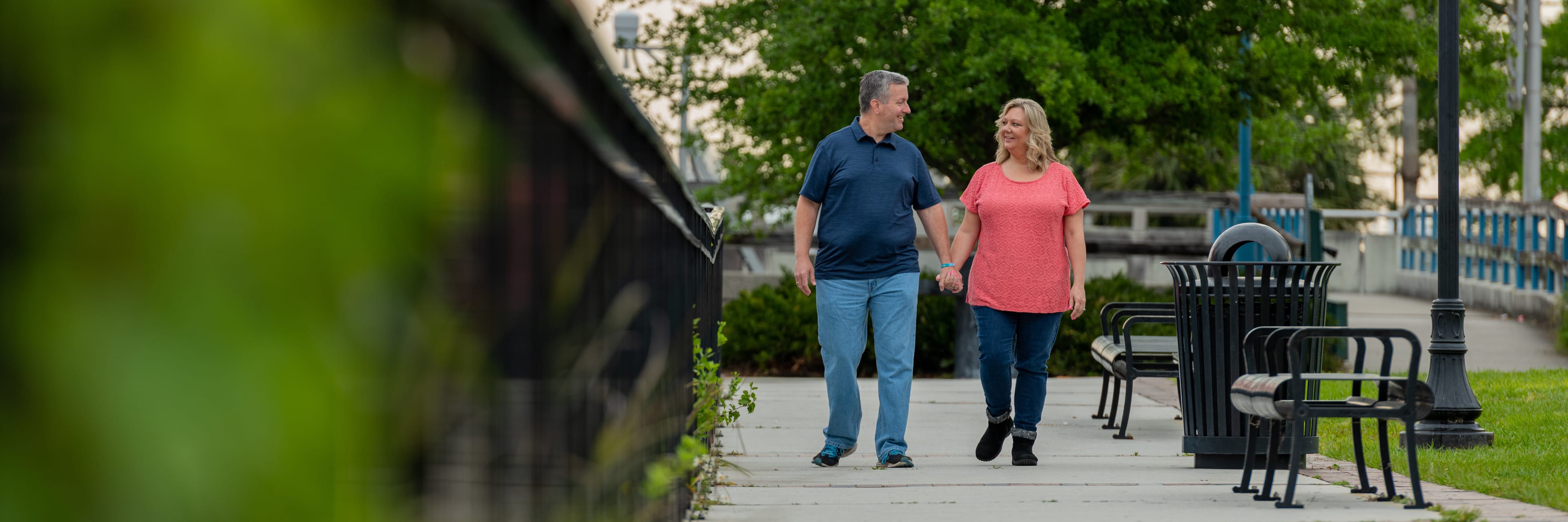 Jacksonville couple that had bariatric surgery happily walking in a park holding hands.