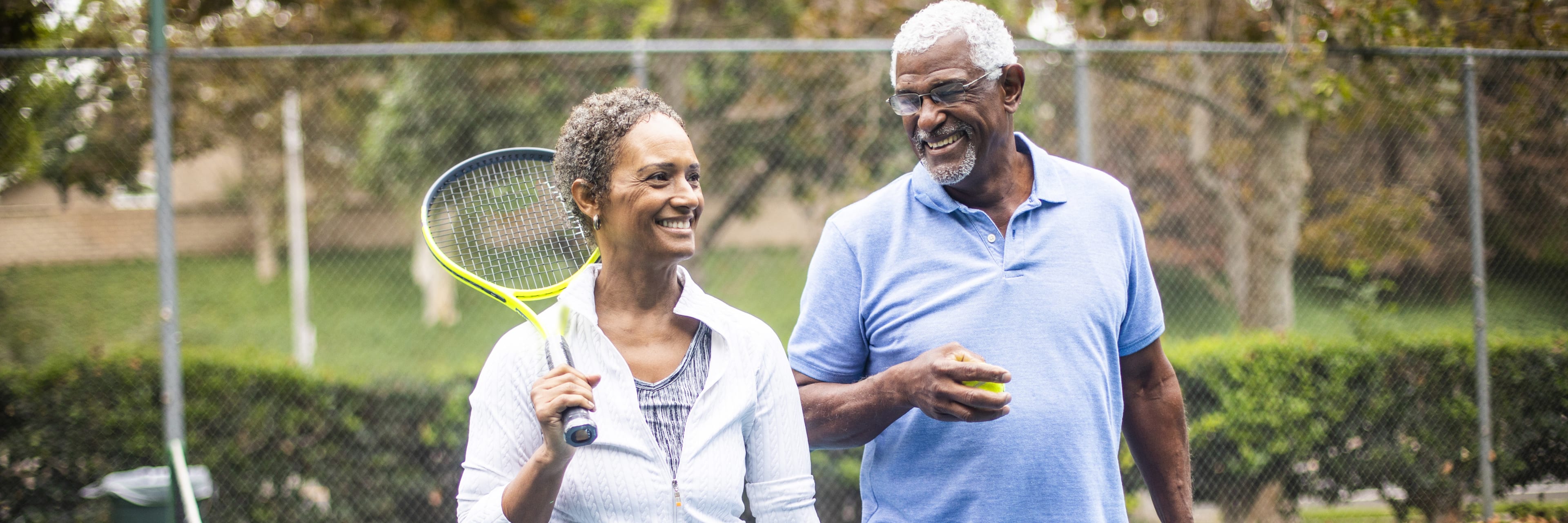 husband and wife happily playing tennis