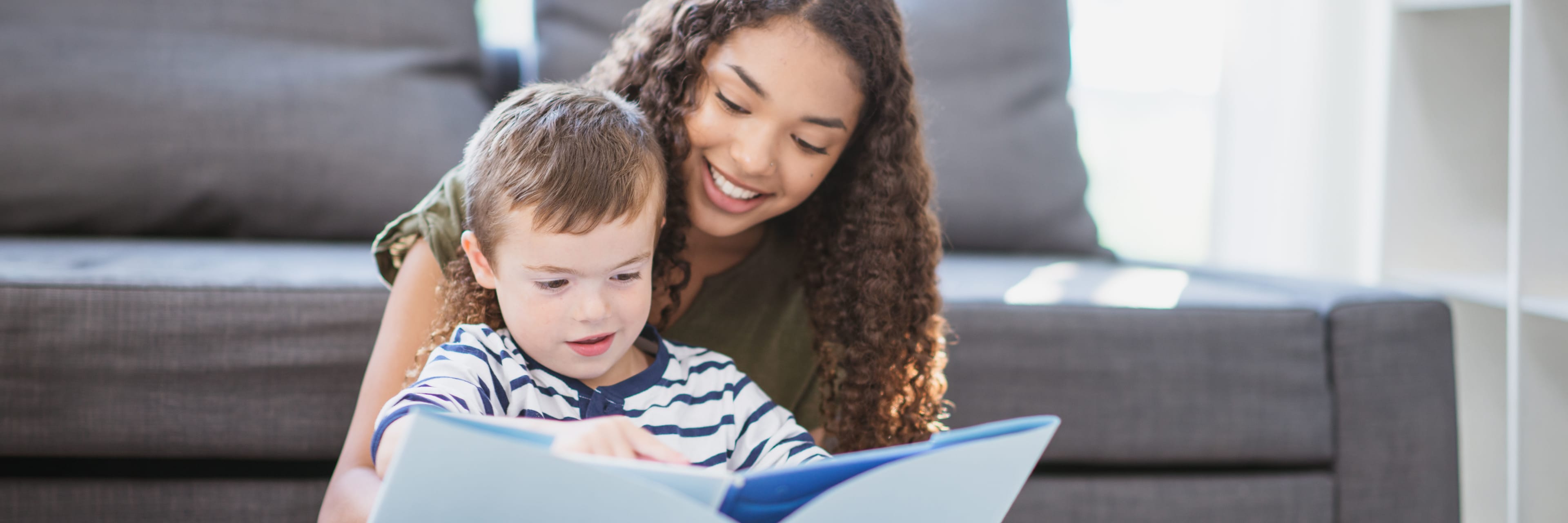teenage girl reads a book to a young boy