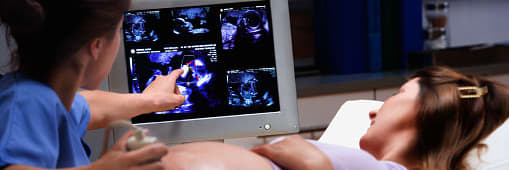a technician is performing an ultrasound on a pregnant woman and points out something to the patient on the monitor