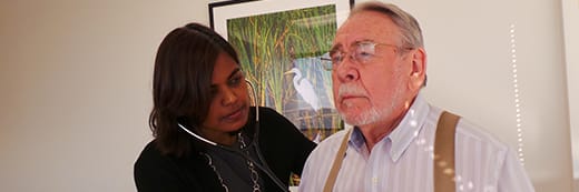 physician checking elderly man's chest with stethoscope