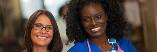 2 smiling female nurses wearing Baptist badges and blue scrubs