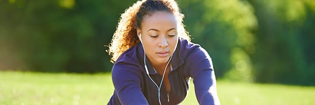 woman with headphones outside stretching her right leg