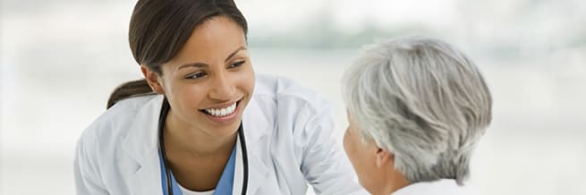 female doctor in a white lab coat offering a comforting smile to an older woman
