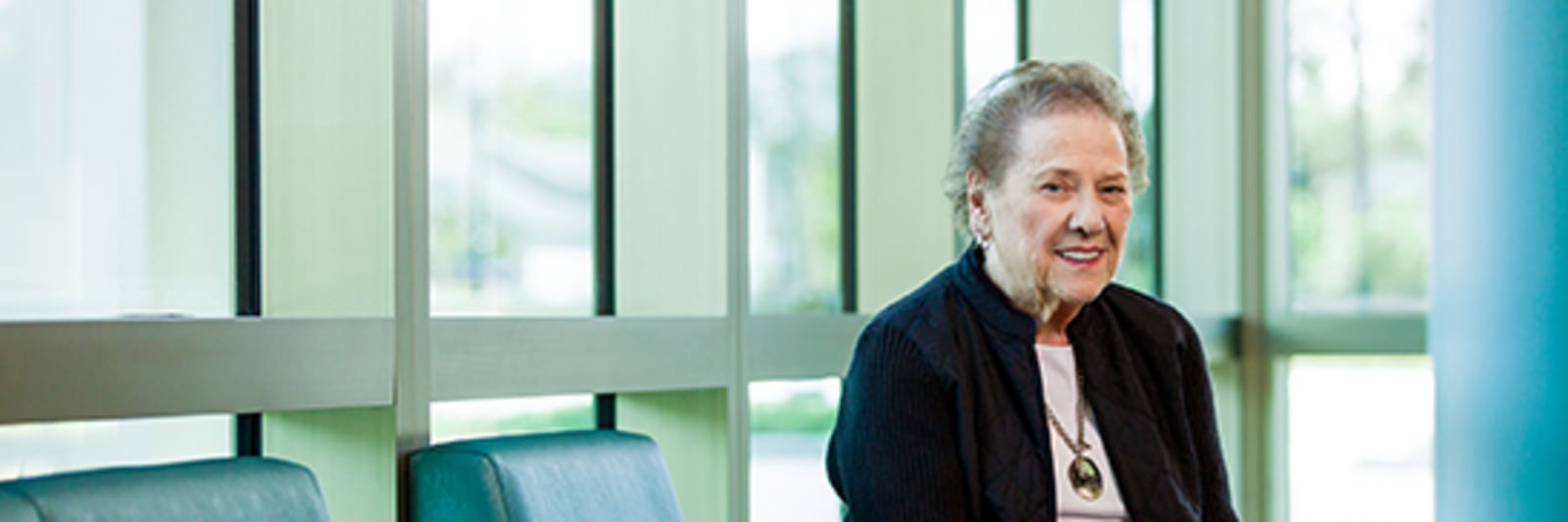 elderly female patient smiles in front of glass windows