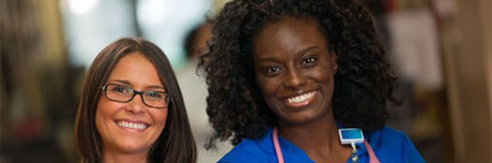 2 smiling female nurses wearing Baptist badges and blue scrubs