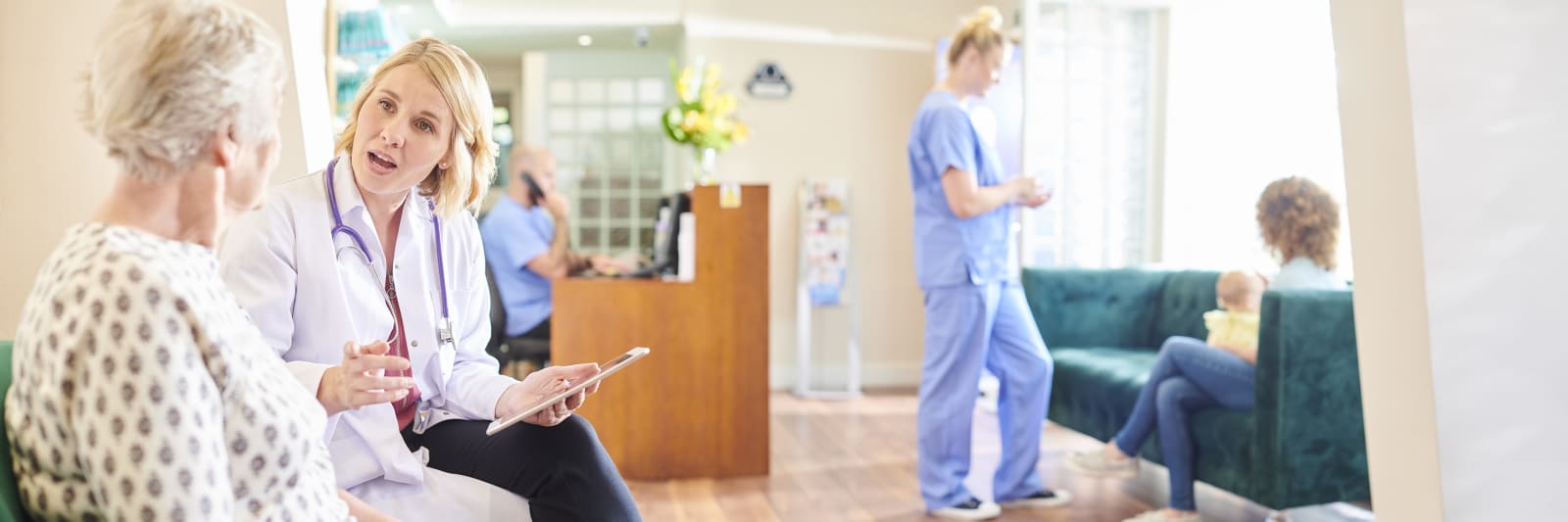 scene inside a doctor's office with patients talking to health care workers.